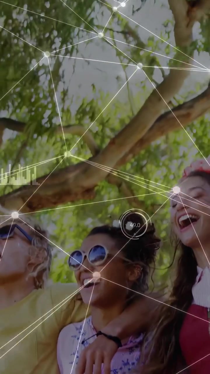 Video verticale: Telecamera riprende amici che ridono sotto un albero, con nodi HUD che etichettano i volti per il marketing.
