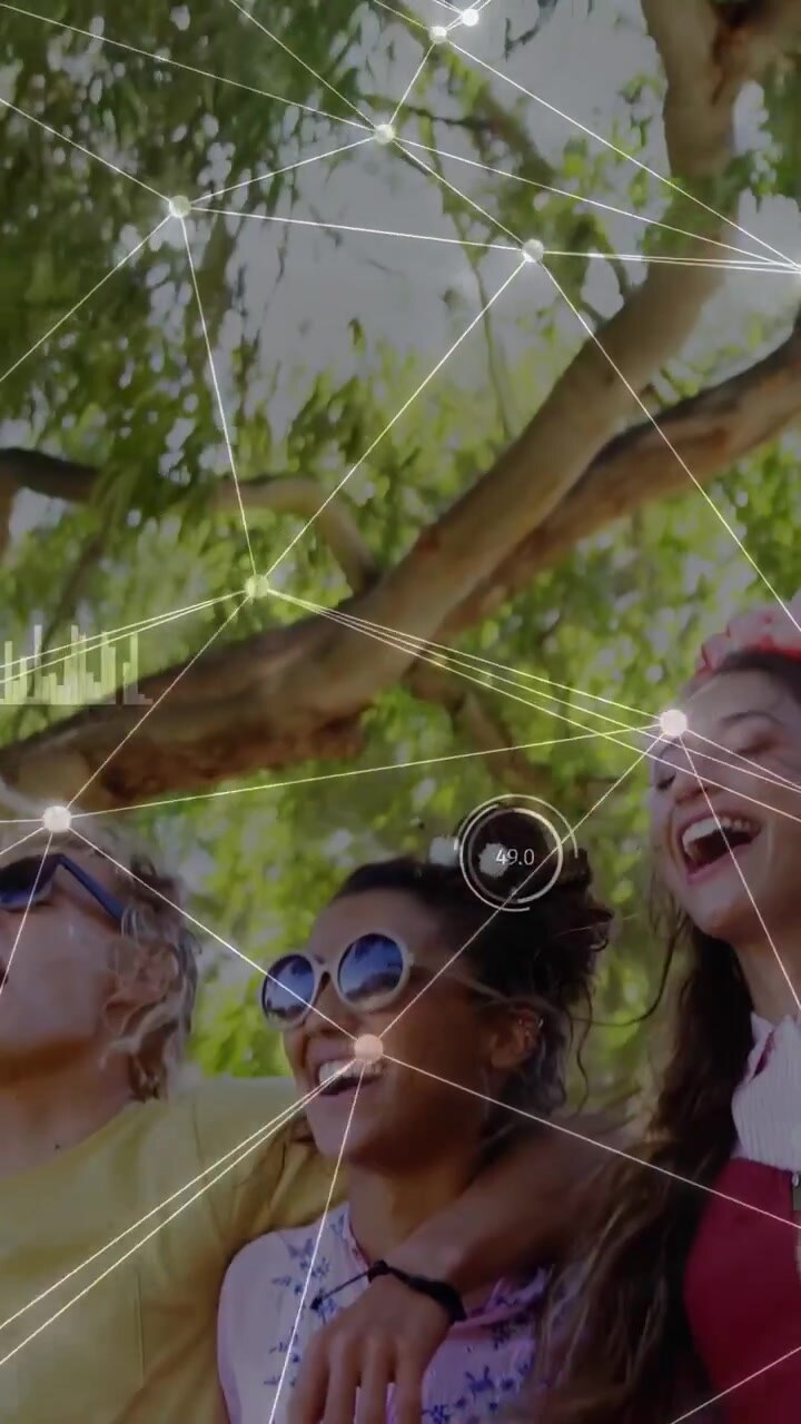 Video verticale: Telecamera riprende amici che ridono sotto un albero, con nodi HUD che etichettano i volti per il marketing.