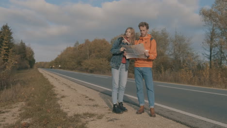 young woman and man backpackers looking at a map