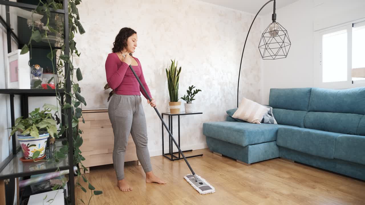 young woman cleaning her living room with a mop