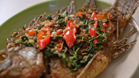 fried tilapia fish with basil chili garlic sauce on top - homemade food style