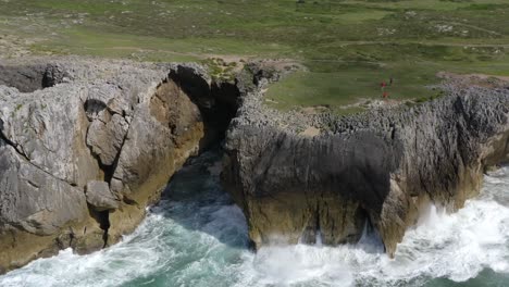 explorers roam on lush green grassy flats above bufones de pria asturias spain sea cliffs