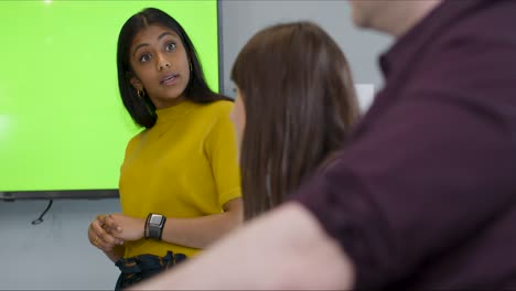 businesswoman discussing with colleagues with green screen tv