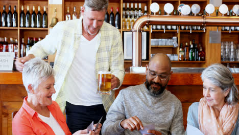 amigos felices jugando a las cartas mientras toman un vaso de cerveza 4k