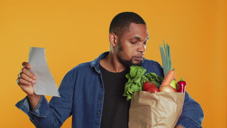 Young adult looking over his grocery shopping list and checking his produce