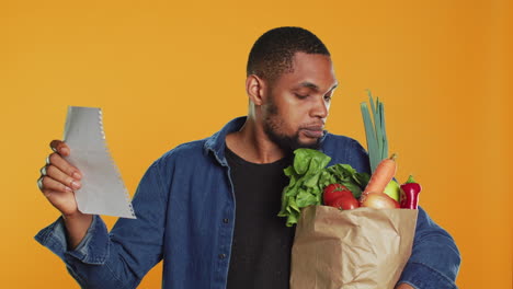 young adult looking over his grocery shopping list and checking his produce