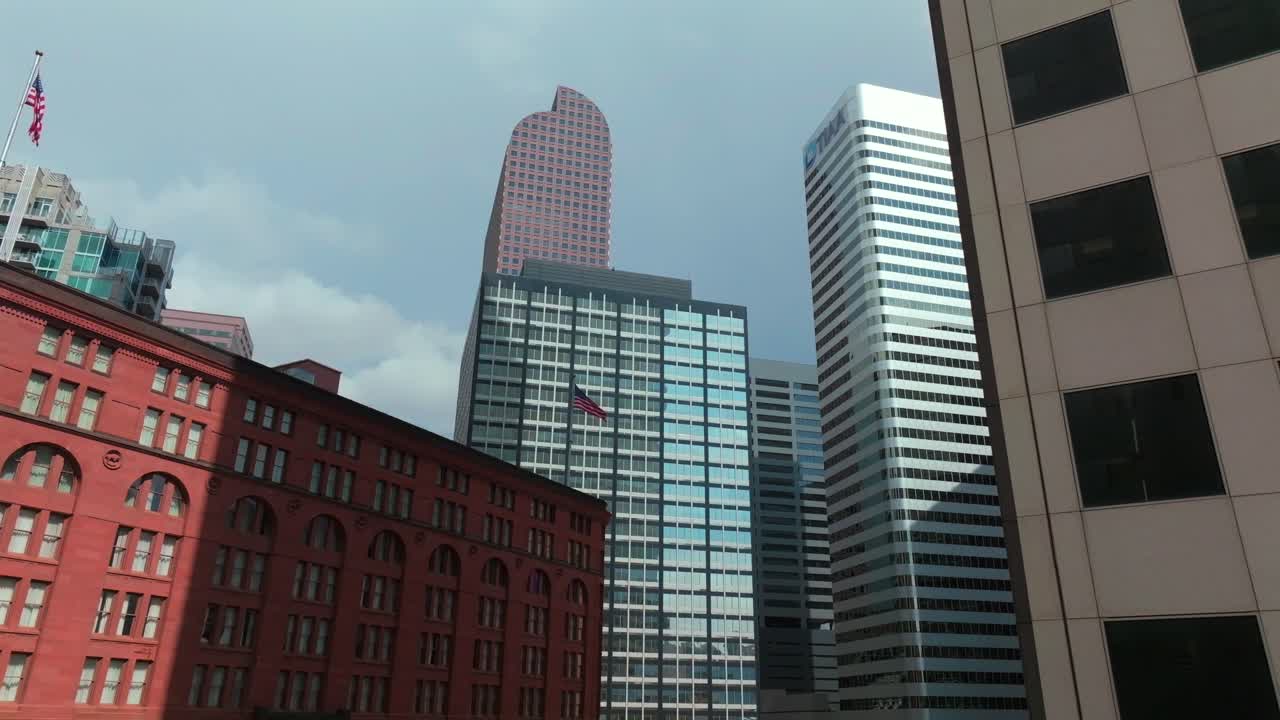 Downtown Denver Brown Palace tall skyscraper buildings cityscape Colorado aerial drone American flag afternoon sunny shade stormy blue skies rain clouds windows Republic Plaza business upwards motion