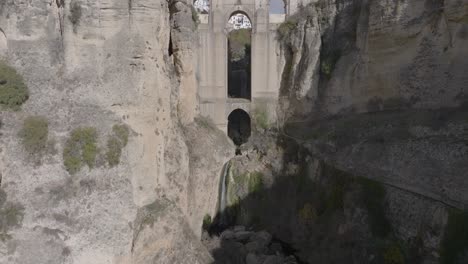 aerial tilt reveals huge arch bridge over deep narrow canyon in spain