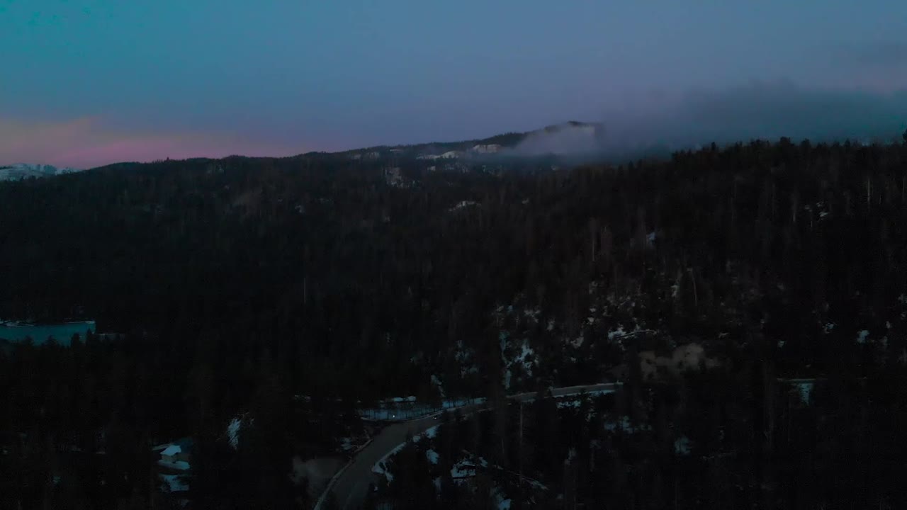 Dron letící nad zasněženou horou za soumraku.