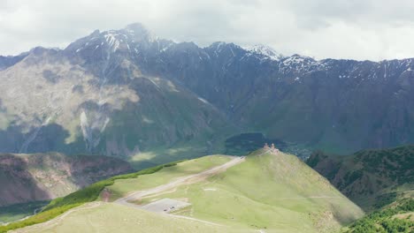 einrichtung einer luftdrohne mit gergeti-dreifaltigkeitskathedrale auf einem hügel mit massiver bergkette im hintergrund