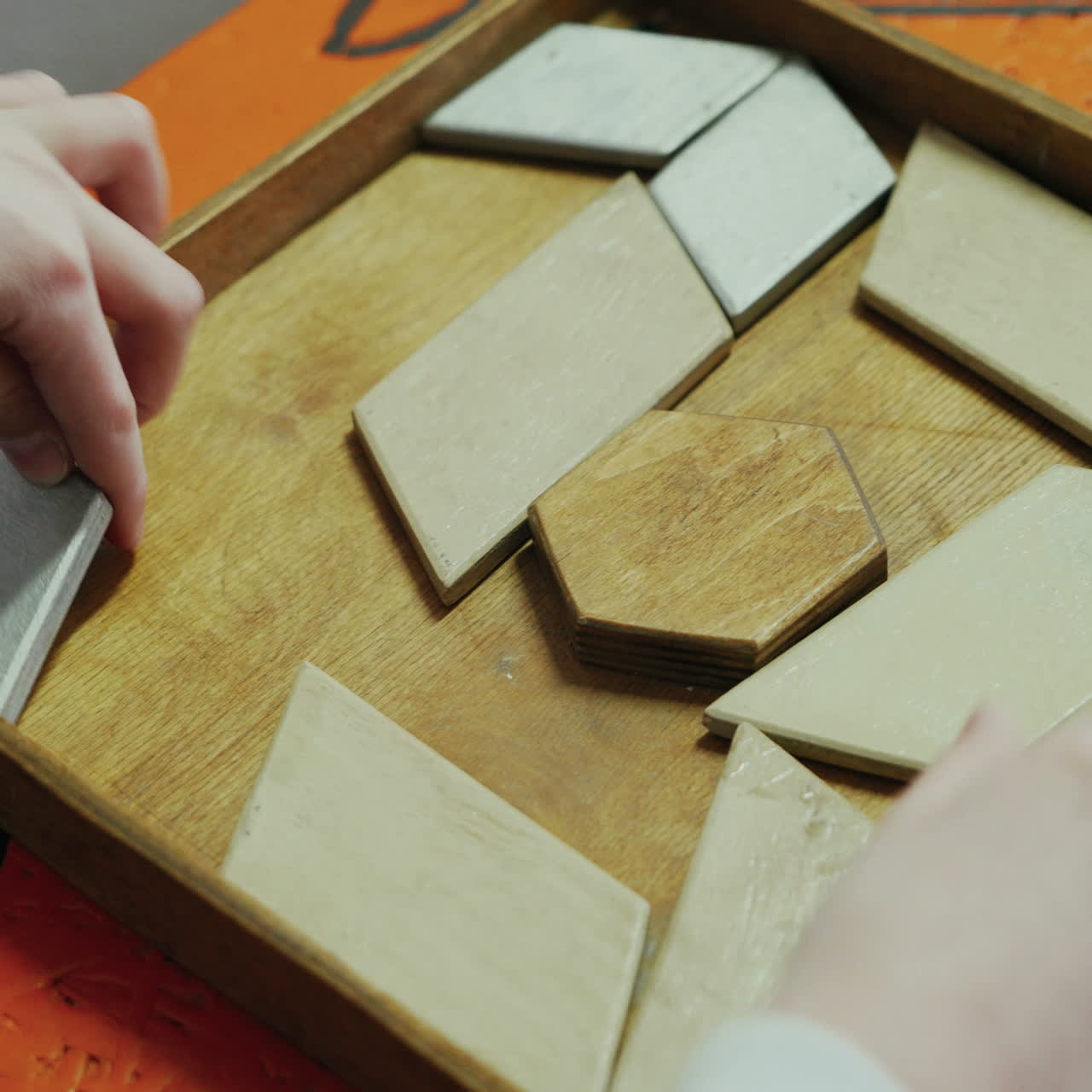 Close-up, hands of a child playing with a wooden puzzle. Concept of education. Square video