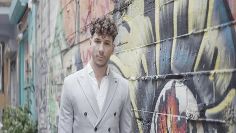 stylish man in a grey suit against a graffiti wall