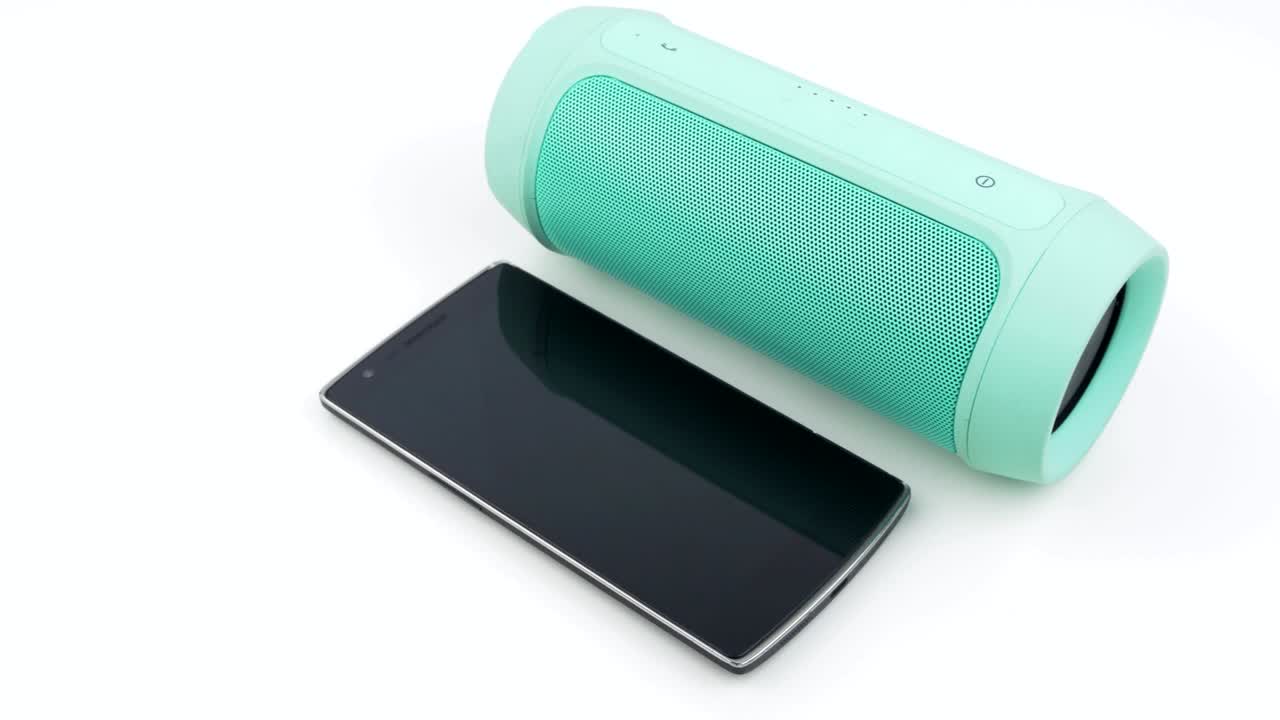 movimiento de panorámica lenta sobre altavoz inalámbrico portátil y teléfono inteligente sobre fondo blanco