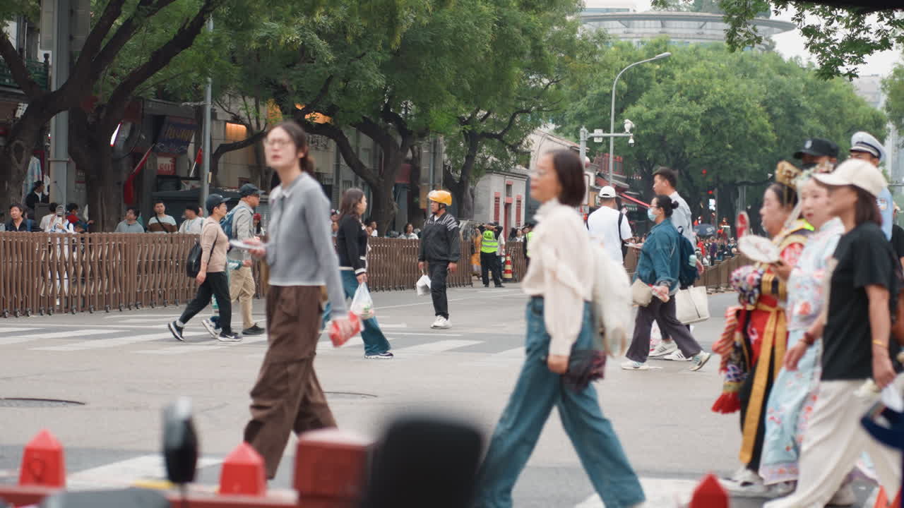 人々が活気ある都会の通りを行き交う。賑やかな大都市圏を人通りが効率的に移動する。警備員が混雑した大通りを家族が安全に渡るのを手助けする
