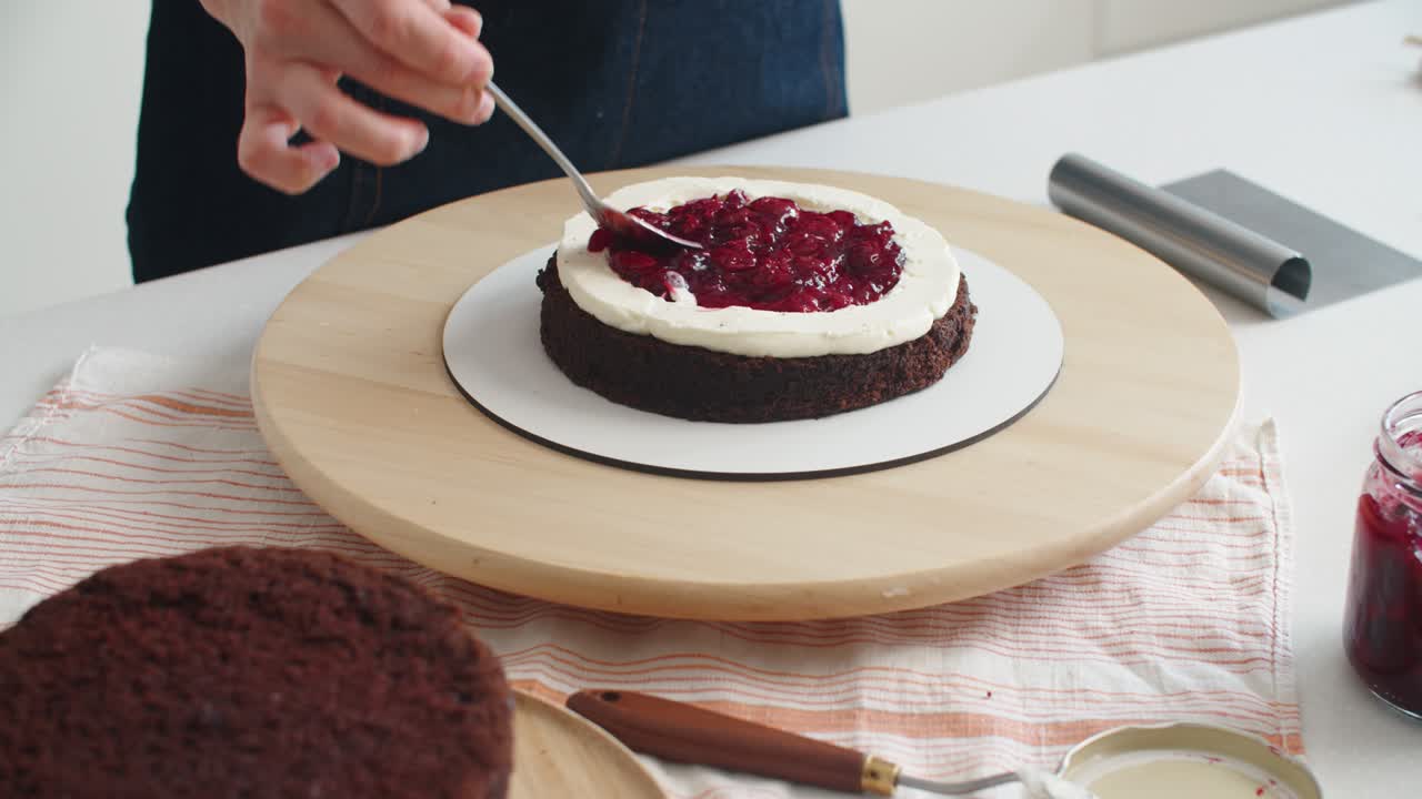 부에서 초콜릿 케이크를 만드는 여성, 클로즈업. 베리를 놓습니다. 여성 손 클로즈 업. 케이크 만드는 과정, 선택적 초점