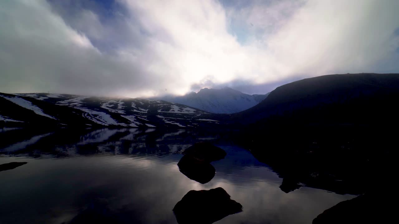 vista de la puesta de sol detrás del pico principal del volcán nevado de toluca al nivel del agua de la laguna lunar con agradables reflejos y rocas en el agua