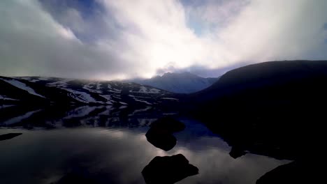 Vista-De-La-Puesta-De-Sol-Detrás-Del-Pico-Principal-Del-Volcán-Nevado-De-Toluca-Al-Nivel-Del-Agua-De-La-Laguna-Lunar-Con-Agradables-Reflejos-Y-Rocas-En-El-Agua