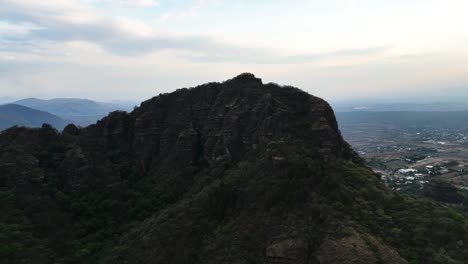 aerial view rising over the tepozteco mountain in cloudy morelos, mexico