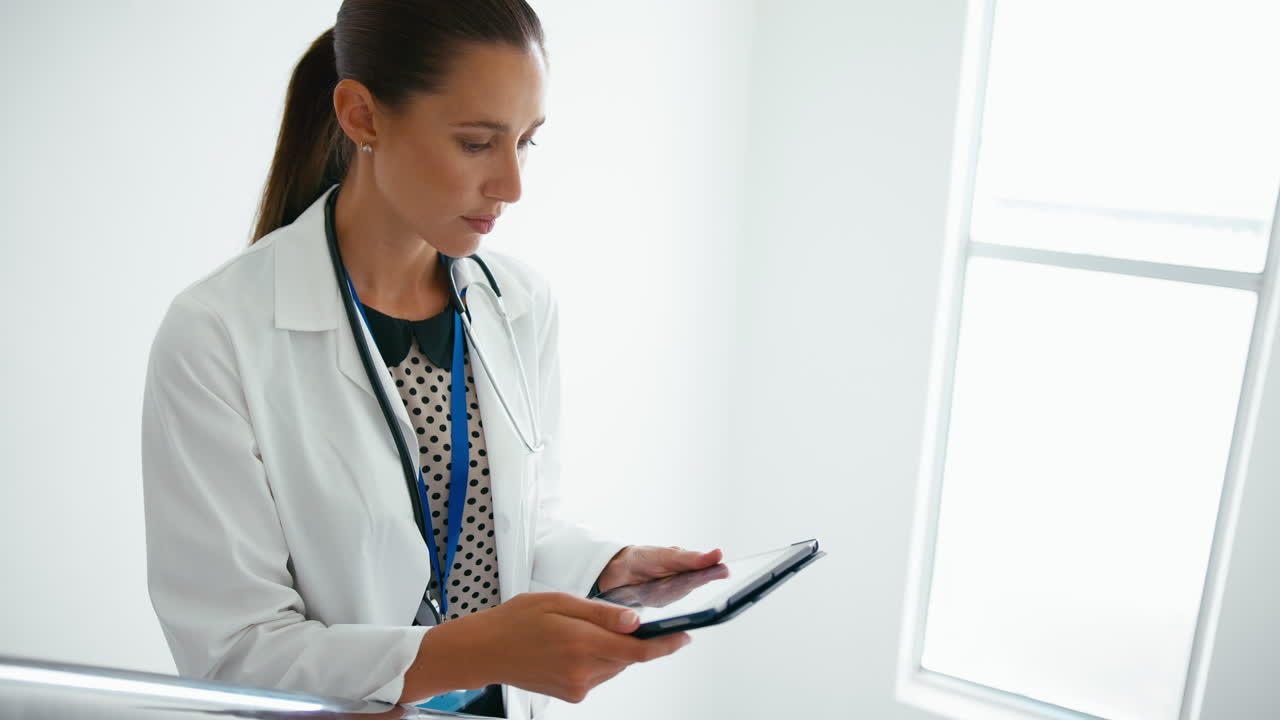 Female Doctor With Digital Tablet Checking Patient Notes On Stairs In Hospital