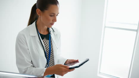 Female-Doctor-With-Digital-Tablet-Checking-Patient-Notes-On-Stairs-In-Hospital