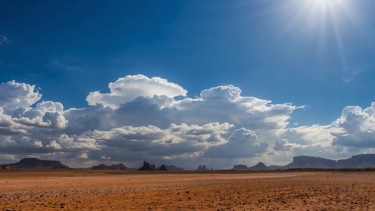Responding to bright sun glare, large layered cumulus clouds slowly expanding over desert plain