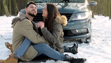 caucasian couple cuddling in the snow during a roadtrip.