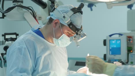 los cirujanos realizan una operación y miran a través de un microscopio móvil
