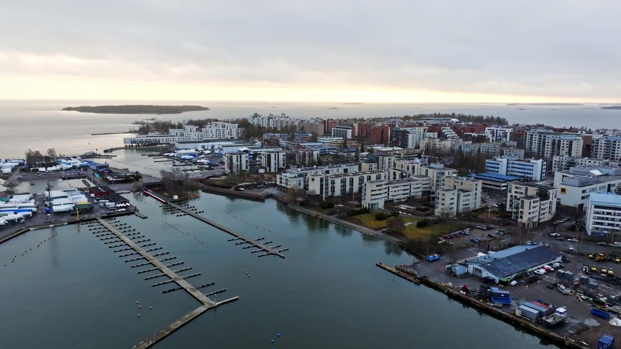 Flygvy som roterar mot stadsdelen Lauttasaari, dramatisk vårsolnedgång.