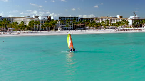 aerial of a small catamaran as it skims the water in front of a luxurious resort in the dominican republic