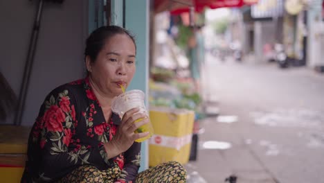 woman sitting outside a vietnamese street vendor shop drinking tea