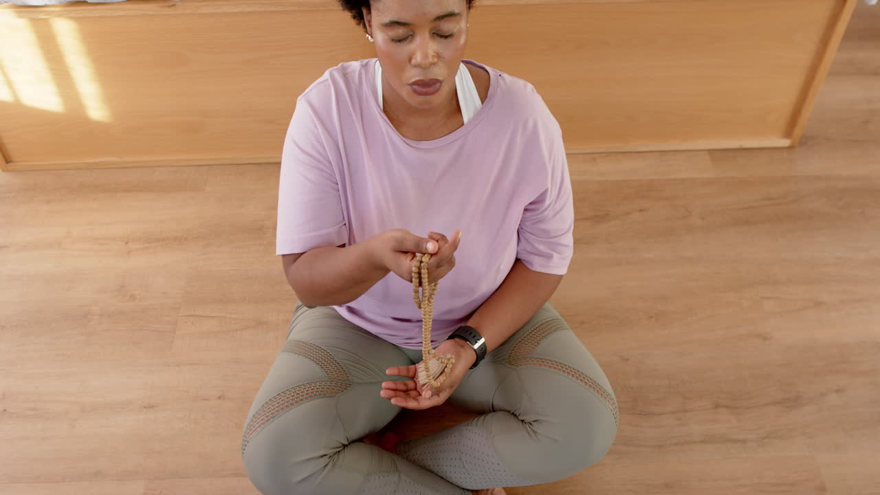 African American woman meditates with beads at home