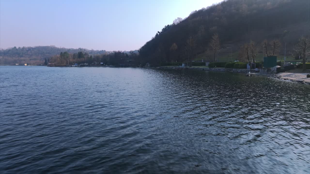 Aerial forward low-altitude flight over rippling blue waters of Lake Orta, Pella, Italy. Drone, copy space