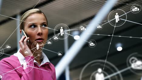 Animation of network of connections with icons over caucasian businesswoman talking on smartphone