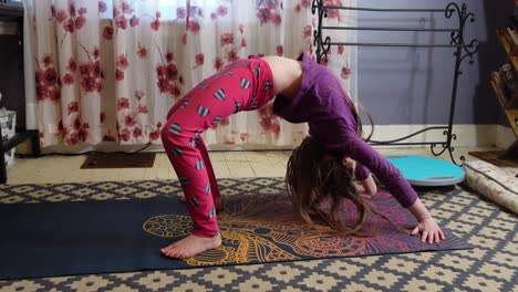 young girl in a mat at home doing stretching during daytime