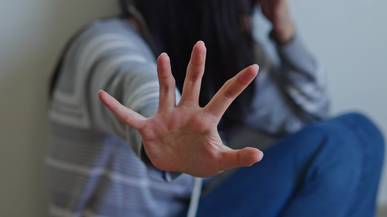 Victim of domestic violence or social issues showing palm to stop gesture
