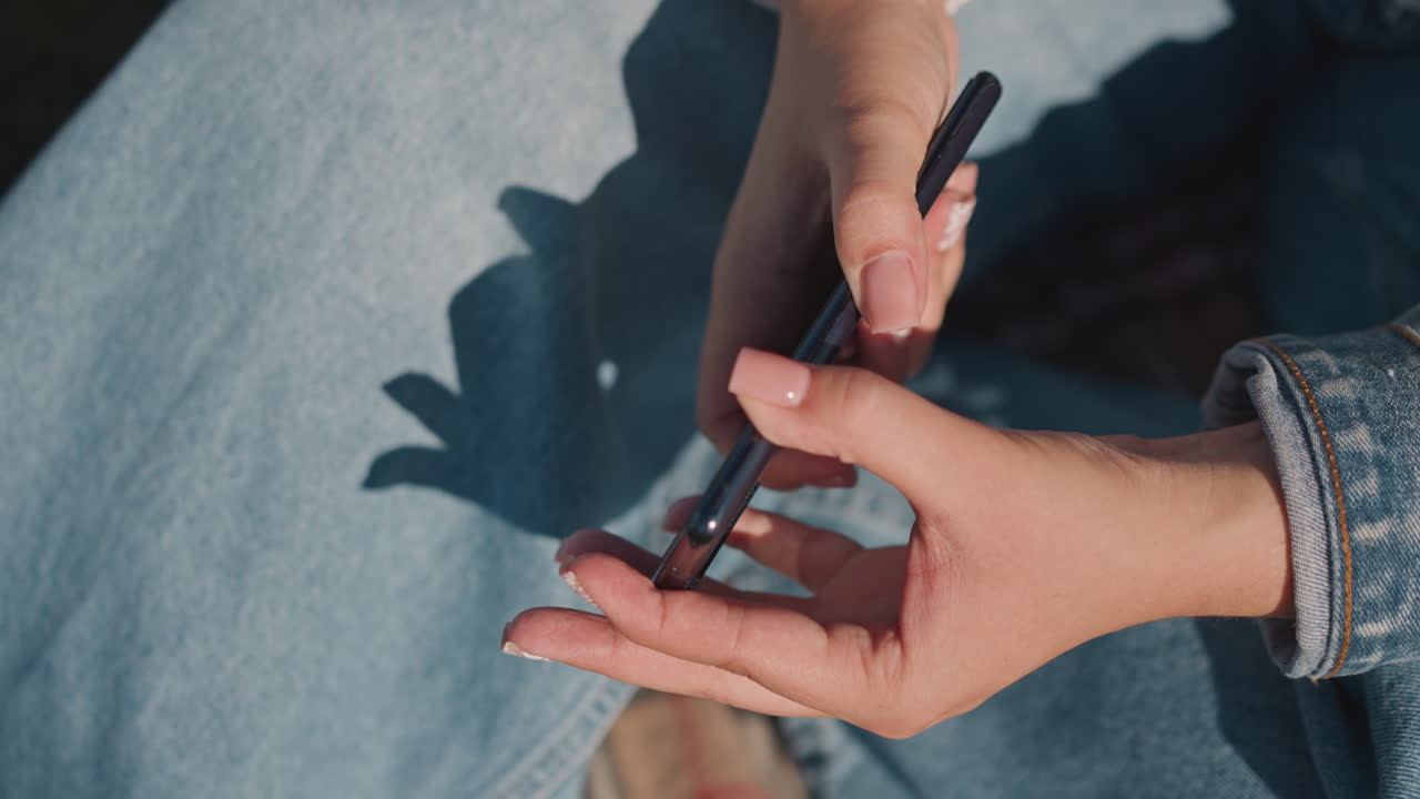 Casual urban scene. Person inspecting wallet with stylus. Individual examining wallet on denim fabric with stylus in hand. Person checks wallet with stylus on textured blanket and denim surface