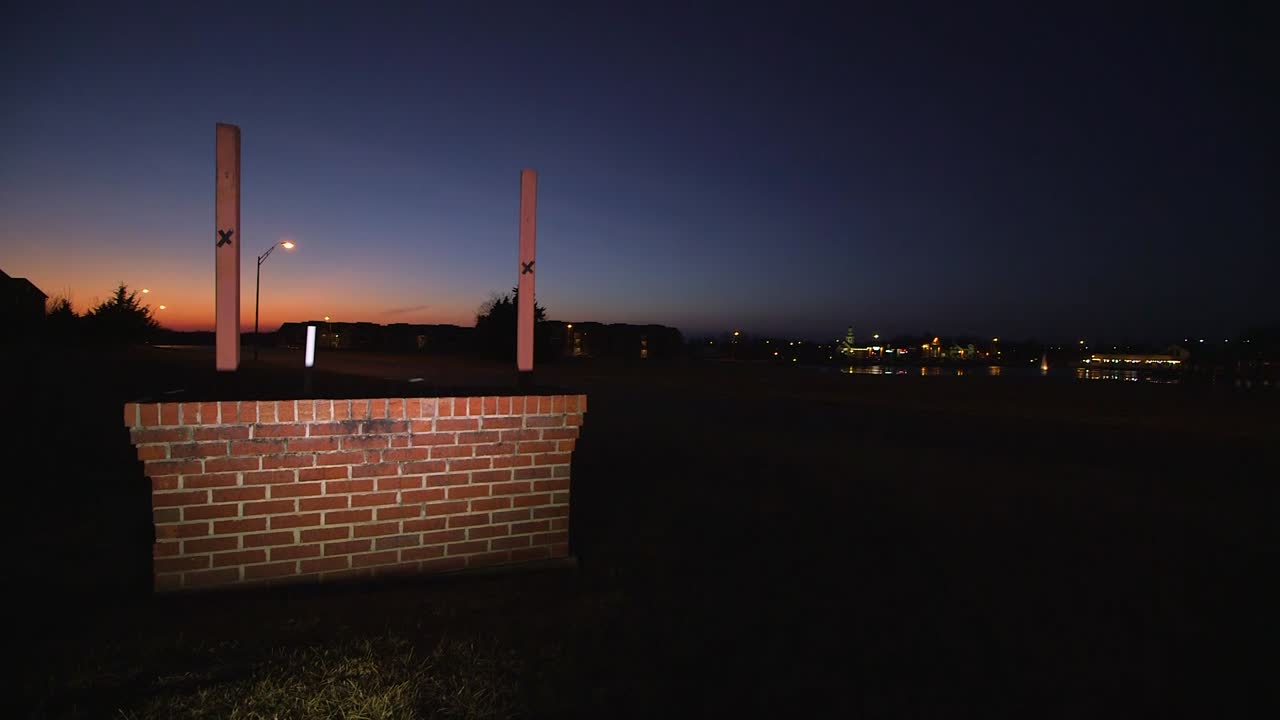 벽돌 플랫폼의 도로 옆에 있는 일몰 근처의 밤에 빈 불이 켜진 표지판