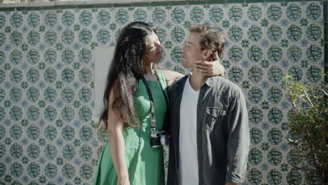 happy multiracial couple standing close, kissing and smiling.