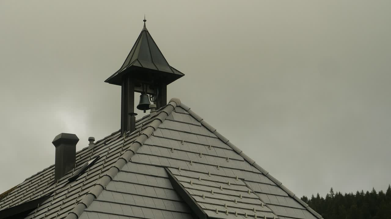 маленький колокол на крыше начинает звонить в облачный день.