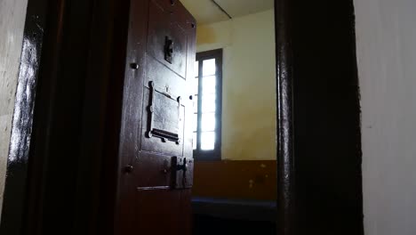 large old wooden heavy jail cell door looking inside cold vintage welsh gaol prison room