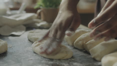 Hands shaping dough on a floured surface