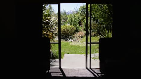 view from inside a home out onto the veranda, green garden and mountains