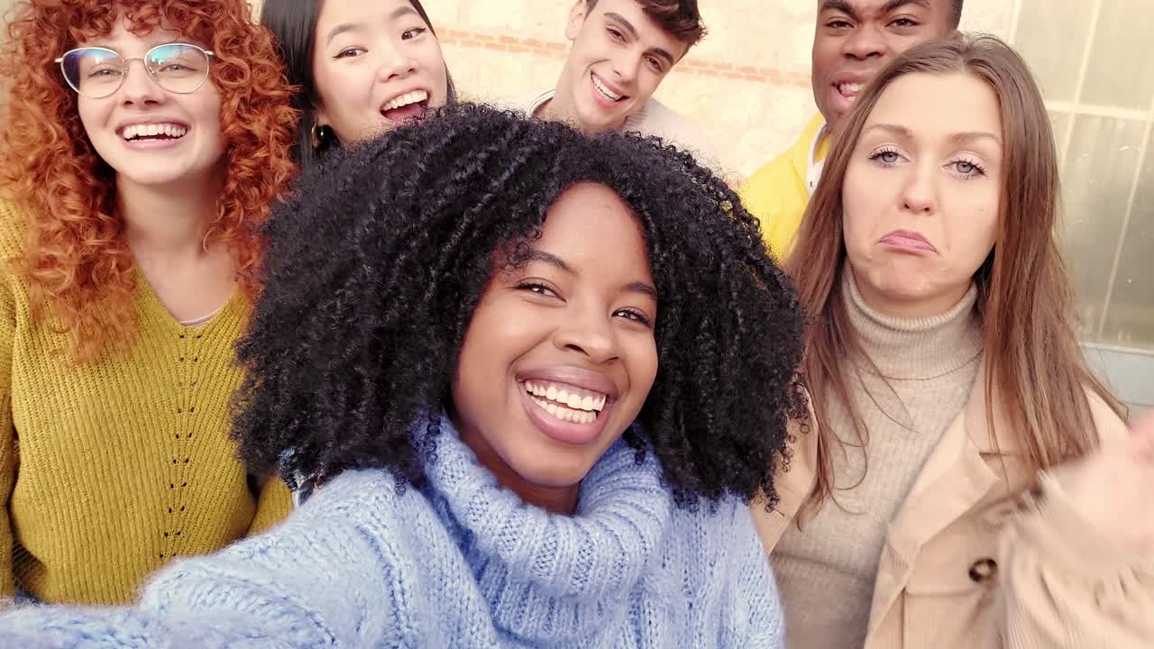 African girl taking a selfie with diverse friends outdoors