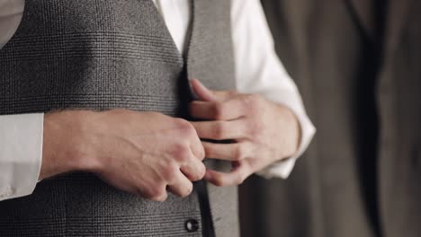 buttoning jacket with hands close up, man in suit fastens buttons on his jacket preparing to go out