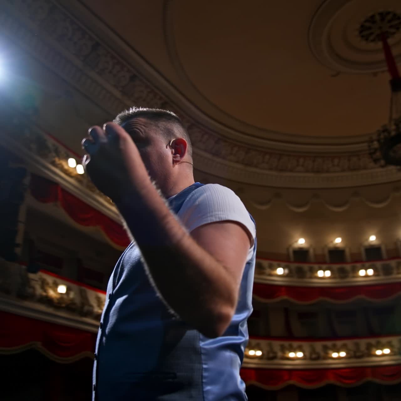 Man on stage gesticulating and talk. Professional actor performing his role on spotlight background in theater. View from stage