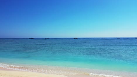 quiet exotic beach with white sand washed by calm clear water of turquoise lagoon and blue sea horizon under bright sky in thailand