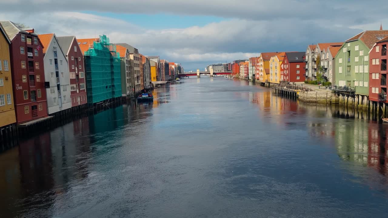 Revealing spring view of Trondheim’s colorful riverside houses along the Nidelva River, their reflections shimmering softly in the calm, gently rippling water