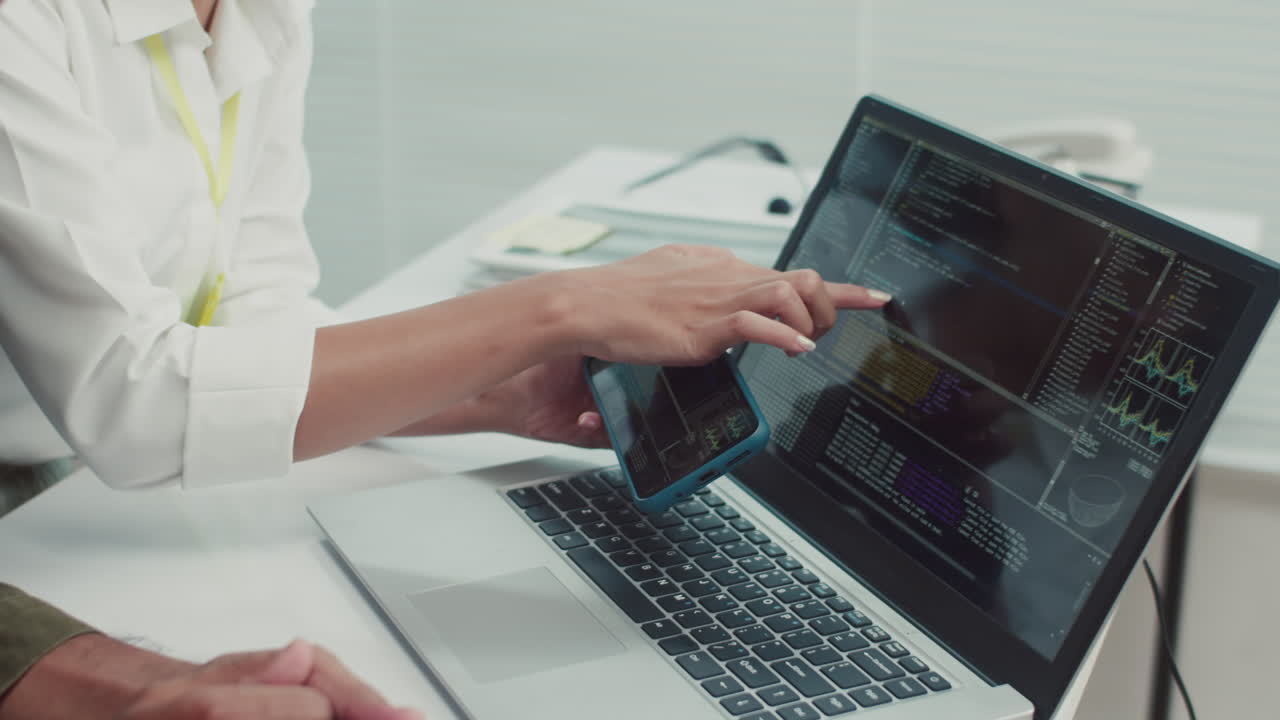 Technician and Client Checking Smartphones Work Using Laptop