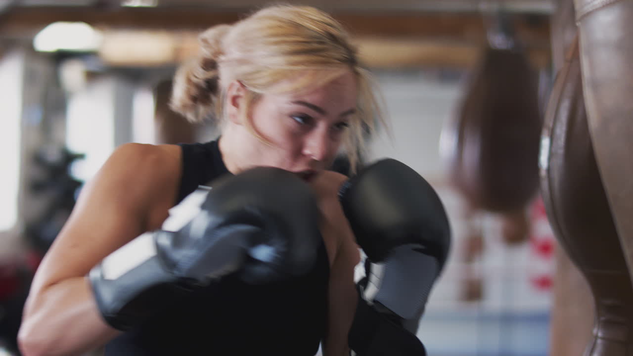 boxeadora en entrenamiento de gimnasio con una bolsa de boxeo de cuero anticuada