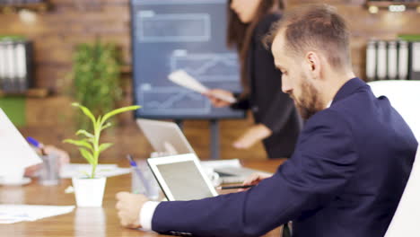 successful young businessman looking at charts on his tablet in the conference room